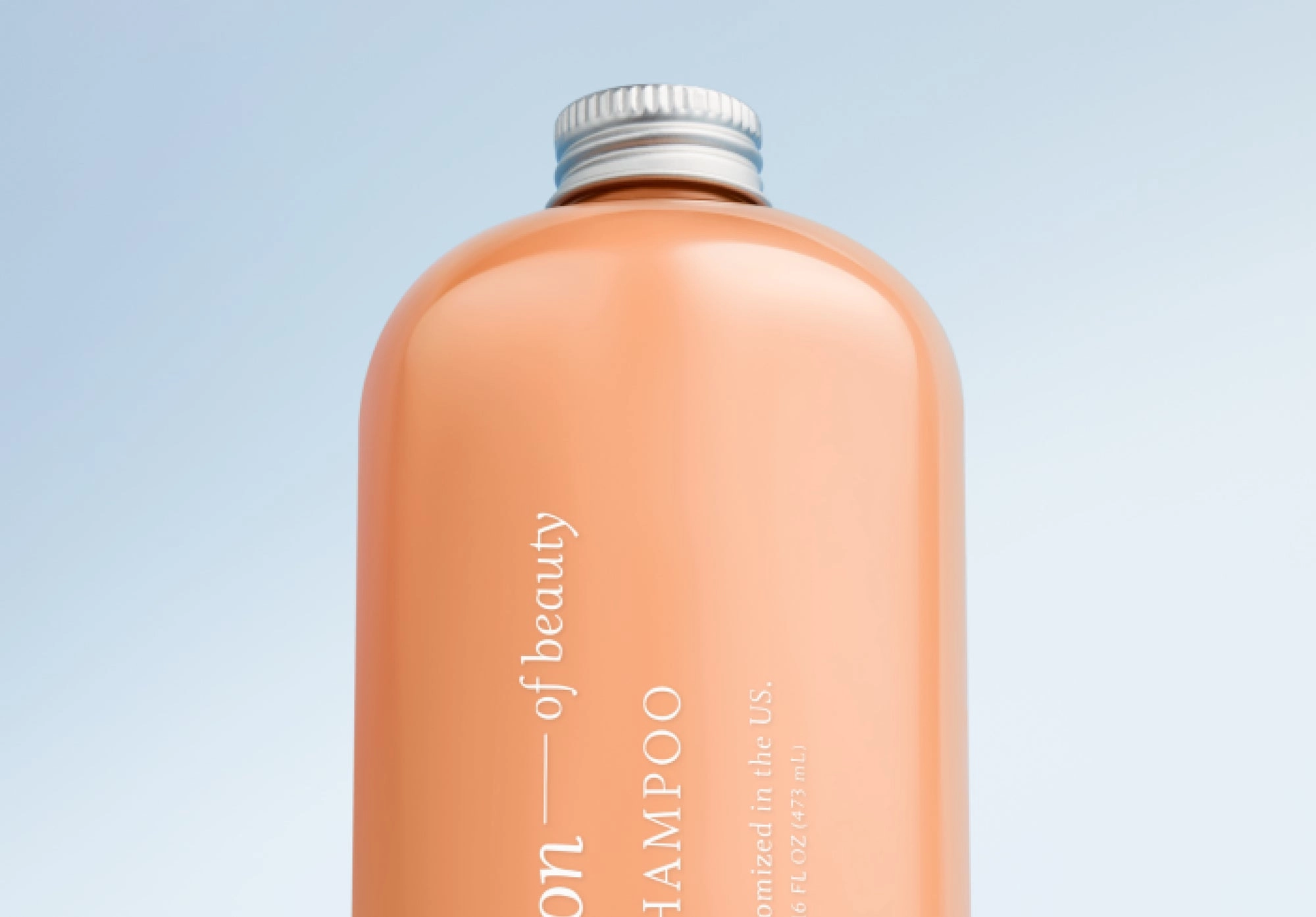 Close view of a peach Function of Beauty bottle against a blue sky