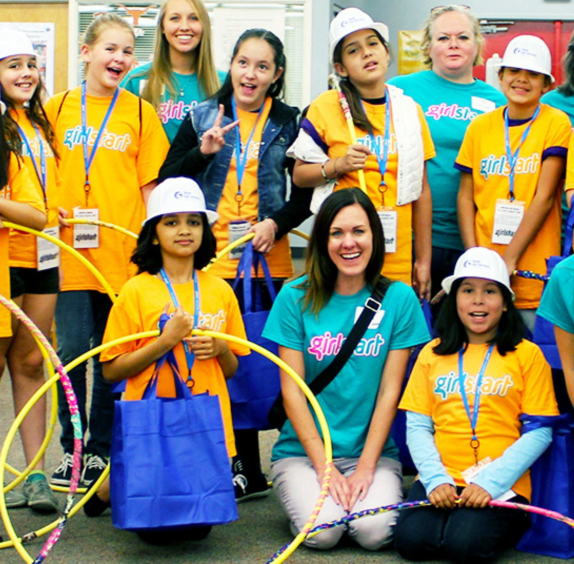 Group of girls and adults in bright yellow shirts and hard hats