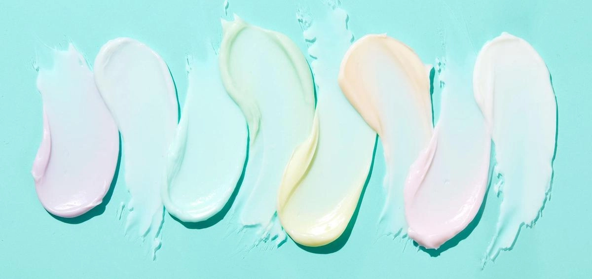 Swatches of hair cream in pastel shades on a mint background