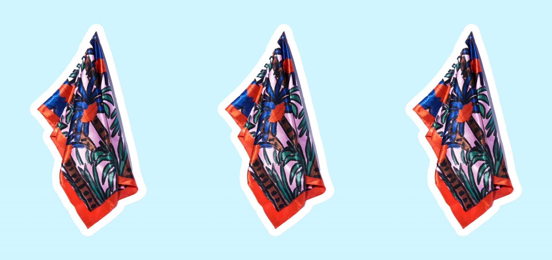Three patterned satin hair scarves on a pale blue background
